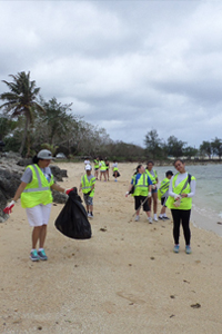 Volunteers for Matson Guam's Adahi I Tano' program pick up trash on the beach.