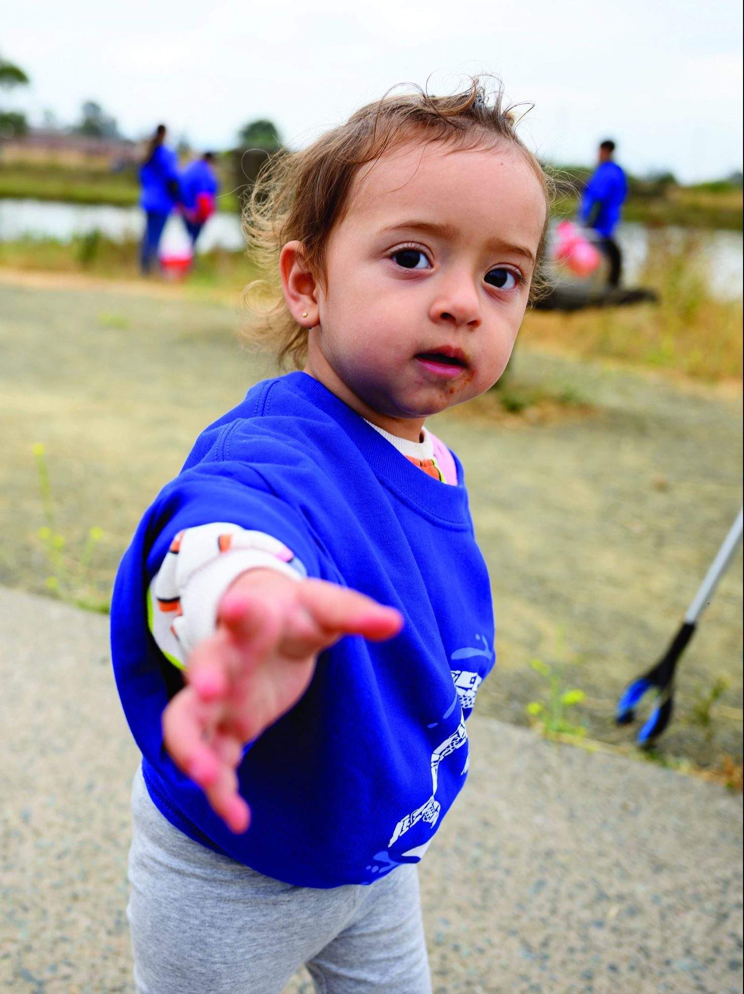A toddler wearing a blue Matson "Sea The Change" t-shirts gives a helping hand at the Oakland Estuary.
