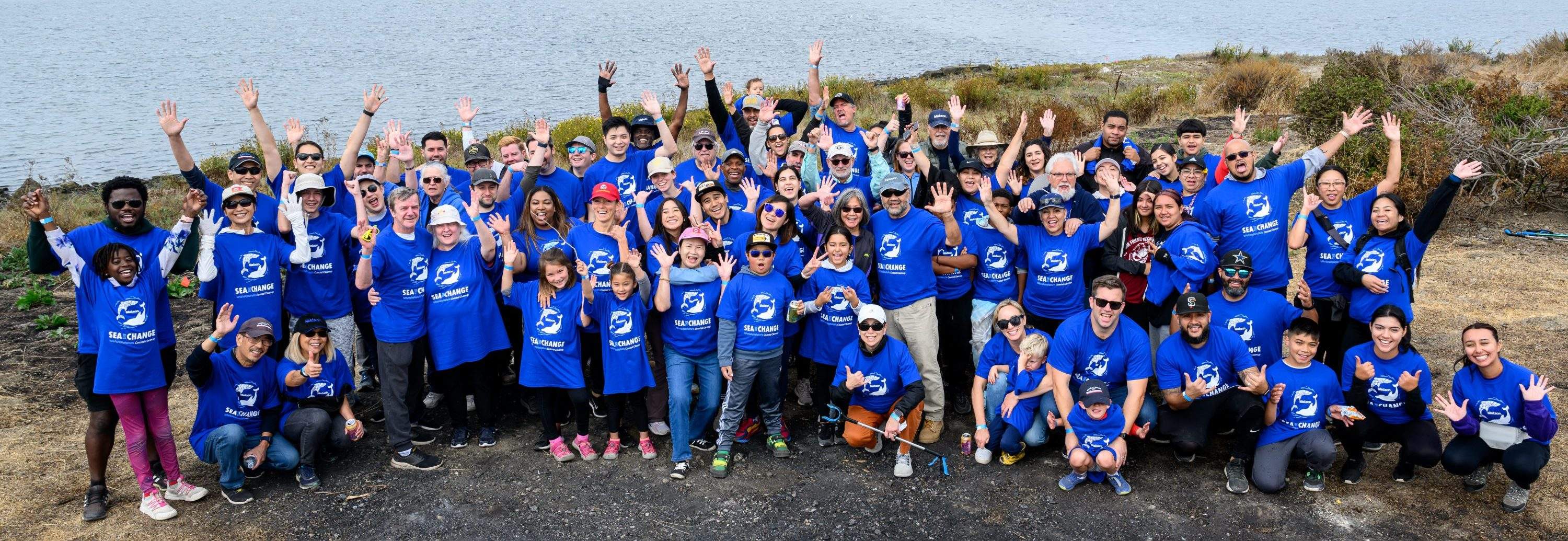 Group picture of Matson volunteers wearing blue "Sea The Change" t-shirts at the Oakland Estuary.