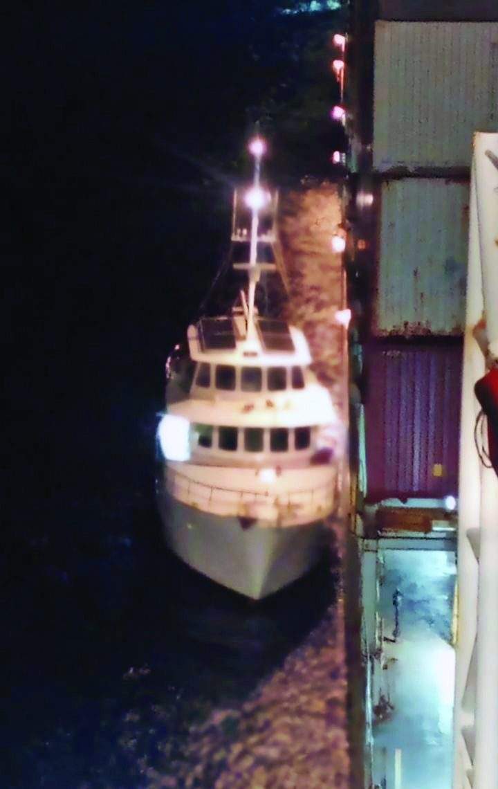 Motor Yacht Eden Bound alongside fully loaded containership Mokihana at night.