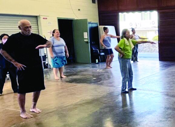 Adults in comfortable clothing participate in hula class.