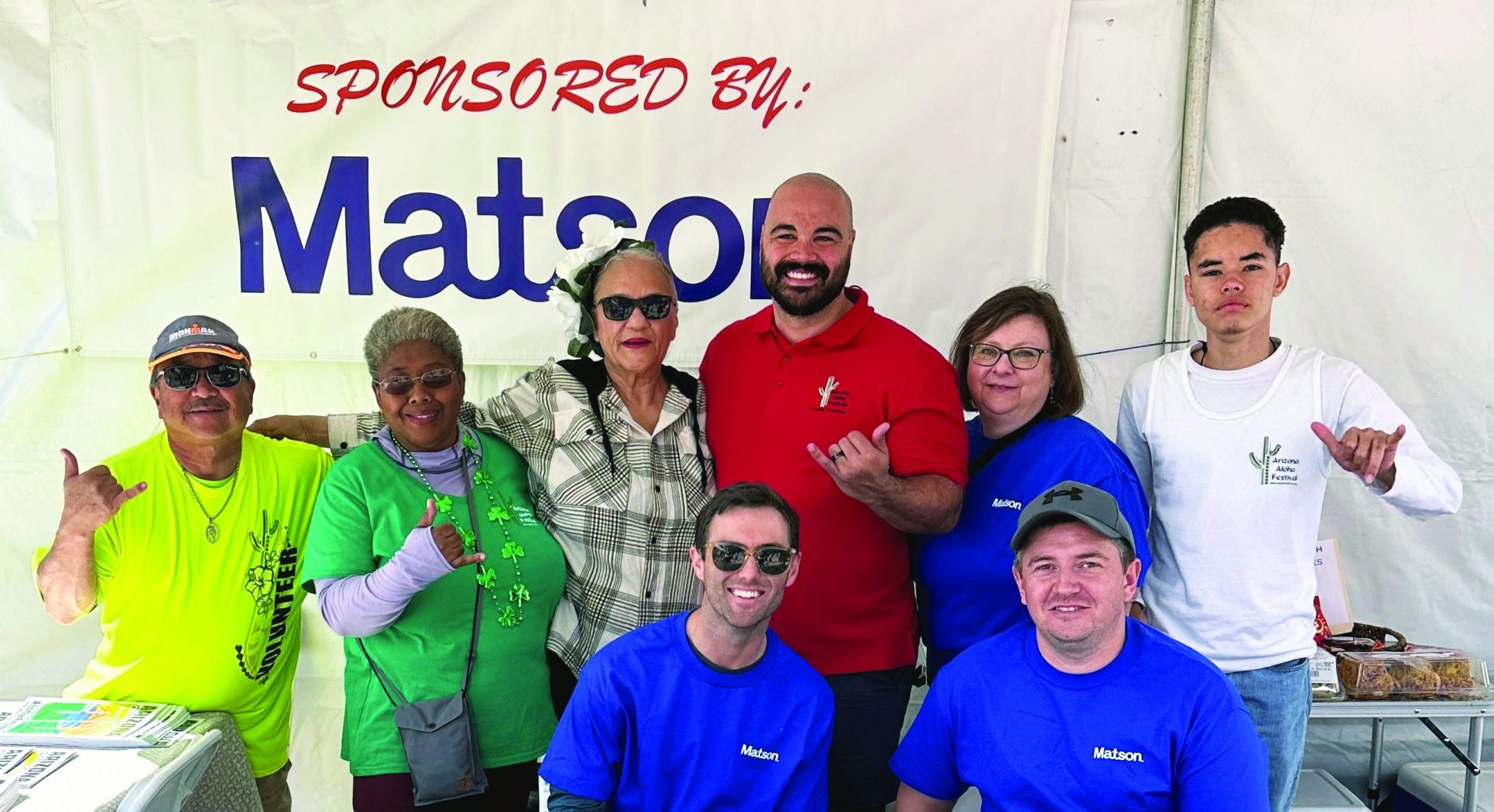 Volunteers at the welcome table stand in front of the Matson logo.
