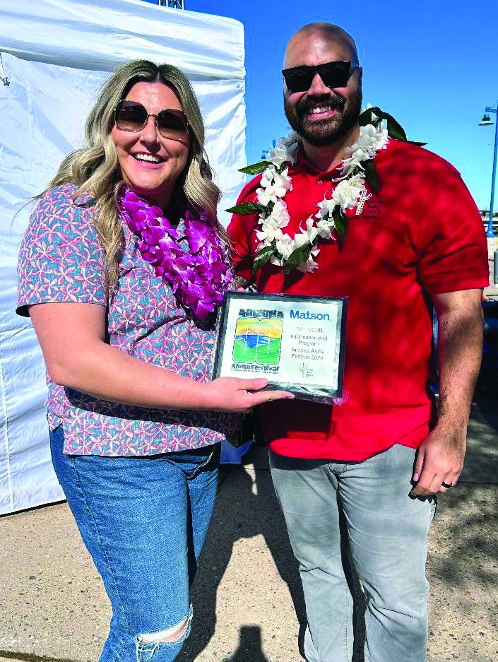 Matson employees wearing sunglasses and adorned with leis hold a frame with the festival's Mahalo award.