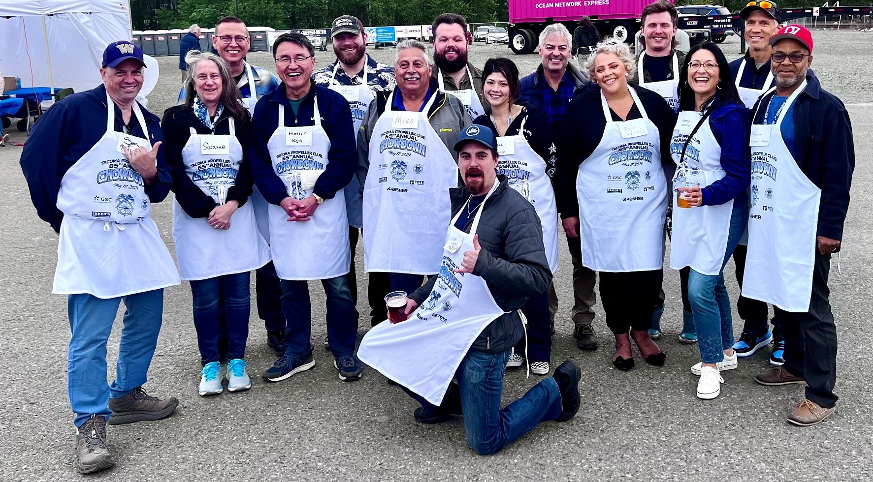 Team Matson wearing white Chowdown event aprons smile for the camera in a parking lot.