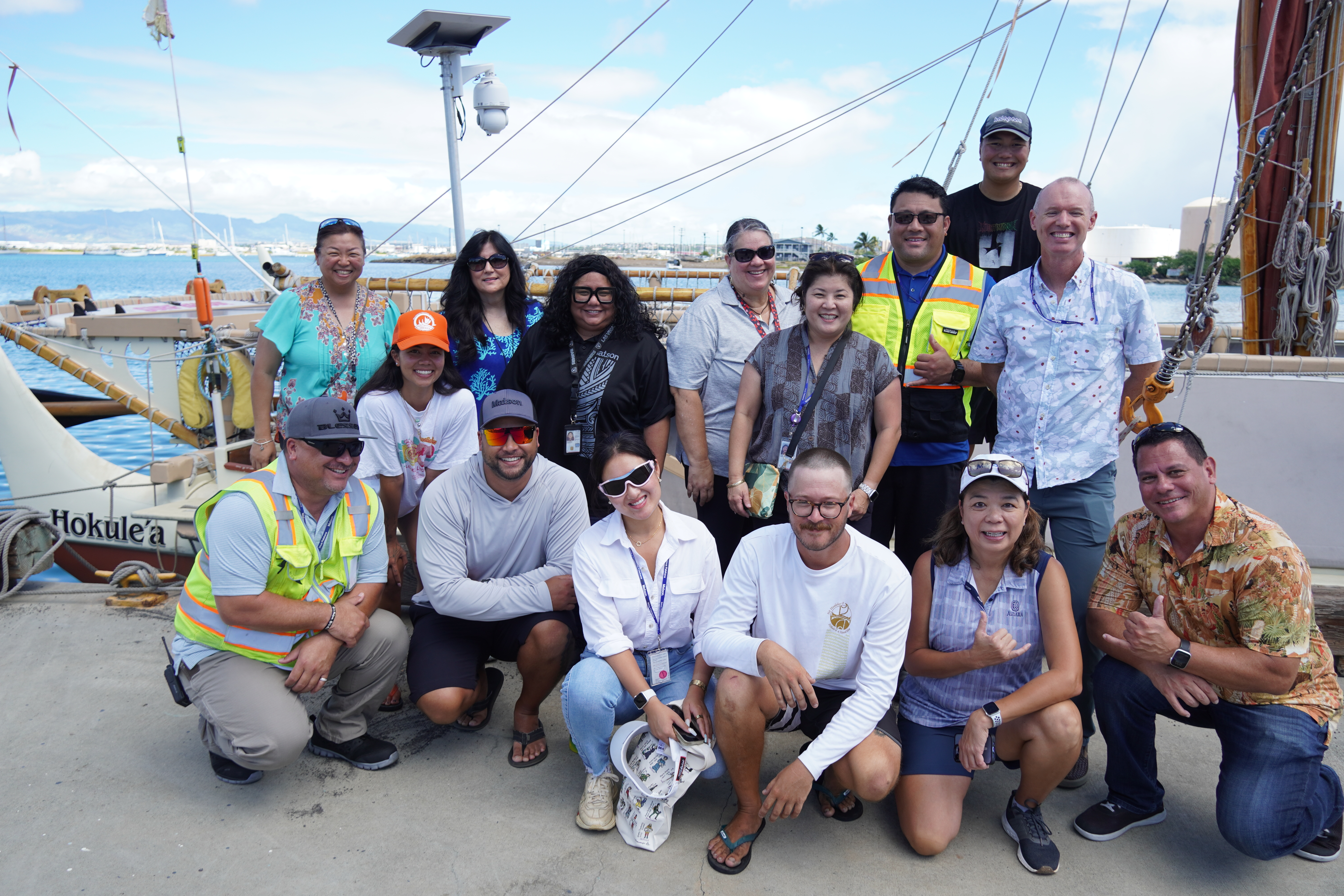 Some Matson Honolulu employees and Hokule'a crew pose in front of Hokule'a.