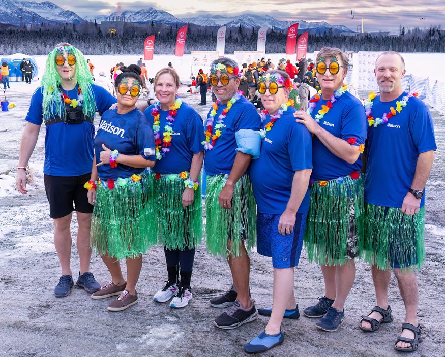 Surrounded by Alaska winter conditions, Team Matson, wearing plastic green grass skirts, colorful leis, and blue t shirts with the Matson logo, ready themselves for the Polar plunge.